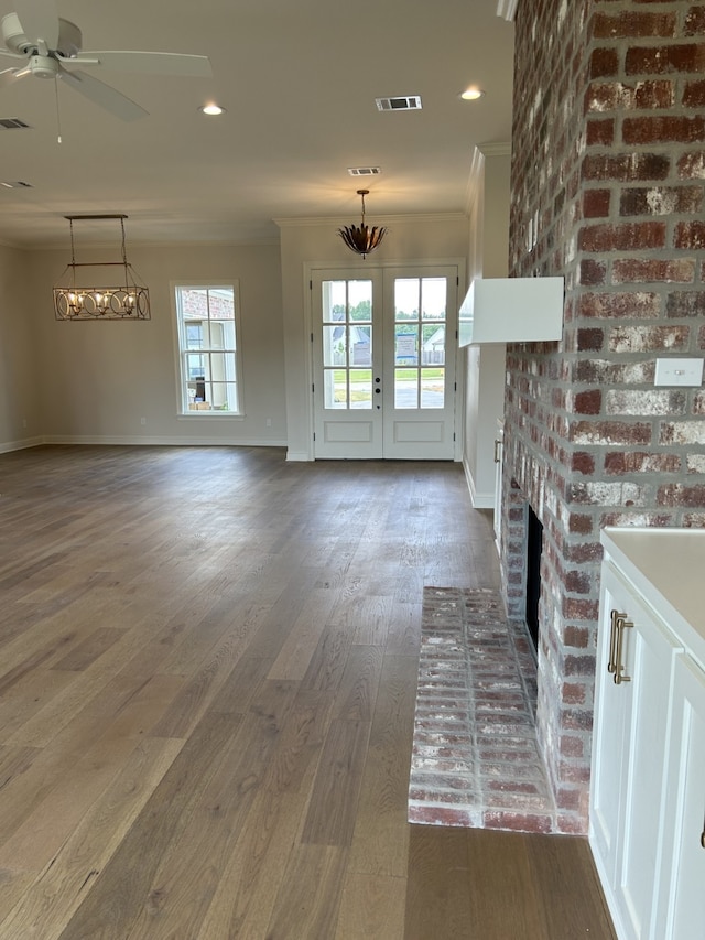 unfurnished living room with visible vents, plenty of natural light, dark wood-style floors, and crown molding