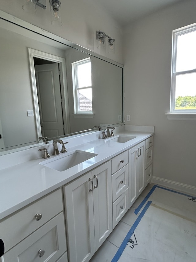 bathroom with double vanity, baseboards, and a sink