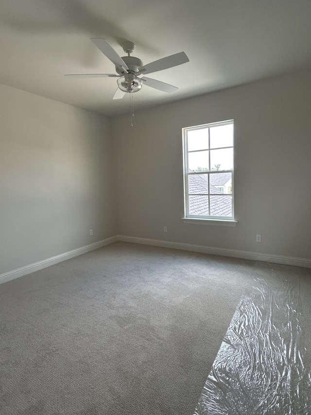 empty room featuring baseboards, carpet floors, and a ceiling fan