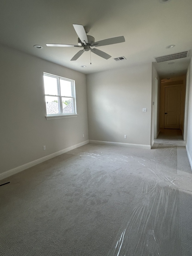 spare room with baseboards, visible vents, and light carpet