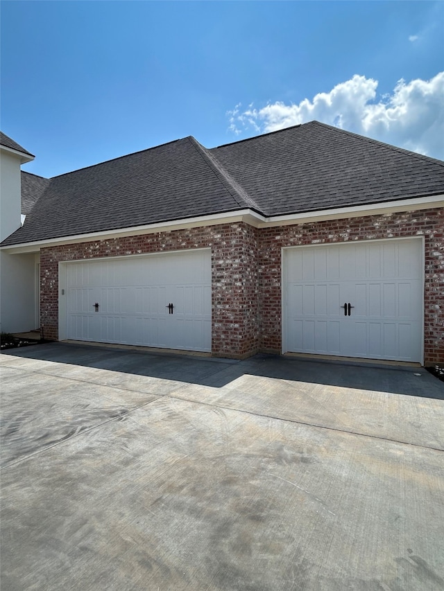 view of front of house featuring brick siding, an attached garage, and roof with shingles