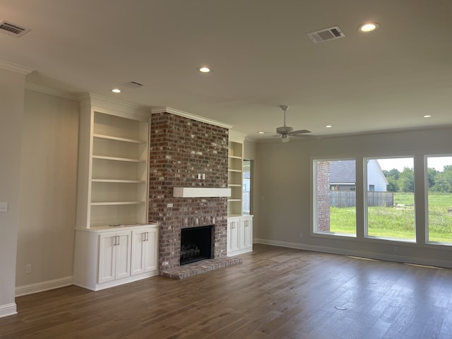 unfurnished living room featuring visible vents, a brick fireplace, dark wood-style flooring, and crown molding