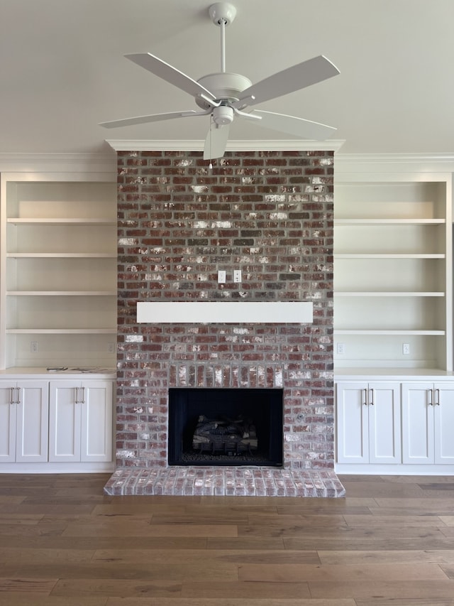 interior details with built in features, wood finished floors, a brick fireplace, and ornamental molding