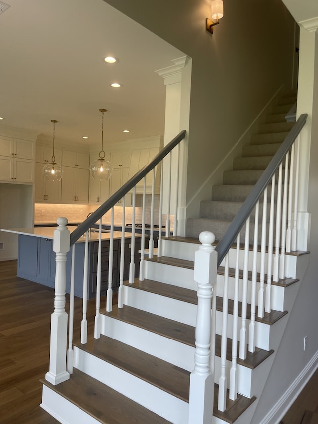 stairway featuring recessed lighting, wood finished floors, and baseboards