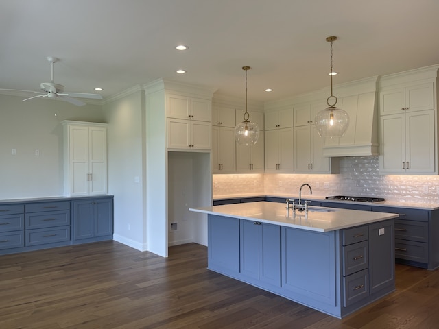 kitchen featuring a sink, stainless steel gas cooktop, light countertops, white cabinetry, and dark wood-style flooring