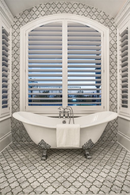 interior space featuring tile flooring, ornamental molding, and a bathtub