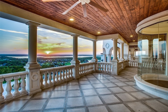 unfurnished sunroom with ornate columns, ceiling fan, wooden ceiling, and a water view