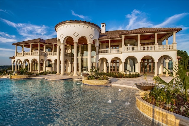 rear view of house featuring a balcony, pool water feature, and a patio