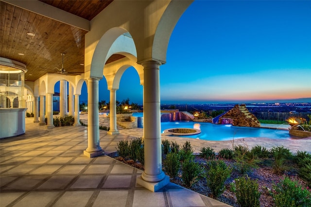 patio terrace at dusk featuring ceiling fan, pool water feature, and a swimming pool with hot tub