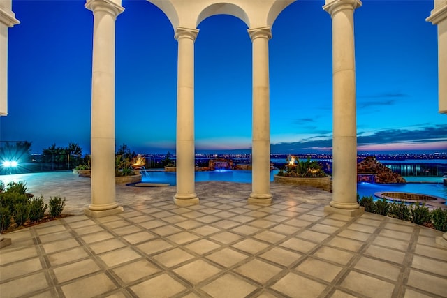 patio terrace at dusk with pool water feature and a community pool