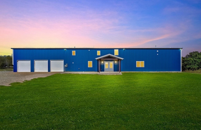 view of front of property with a garage, a yard, and french doors