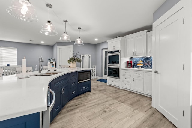 kitchen with decorative backsplash, stainless steel double oven, white cabinets, black microwave, and sink