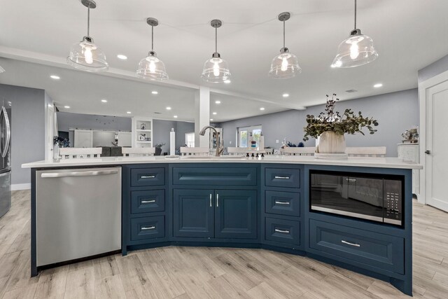 kitchen with blue cabinetry, stainless steel dishwasher, black microwave, light hardwood / wood-style flooring, and decorative light fixtures