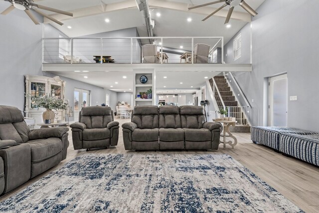 living room with ceiling fan, high vaulted ceiling, and light hardwood / wood-style flooring