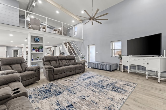 living room with light hardwood / wood-style flooring, ceiling fan, and a high ceiling