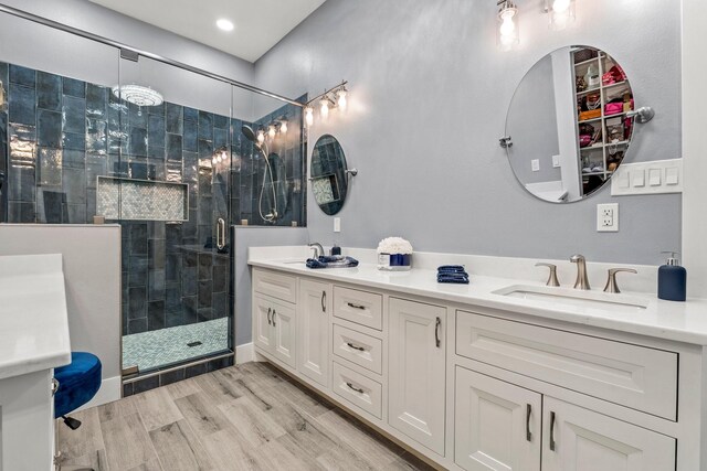 bathroom with double sink vanity, wood-type flooring, and a shower with shower door