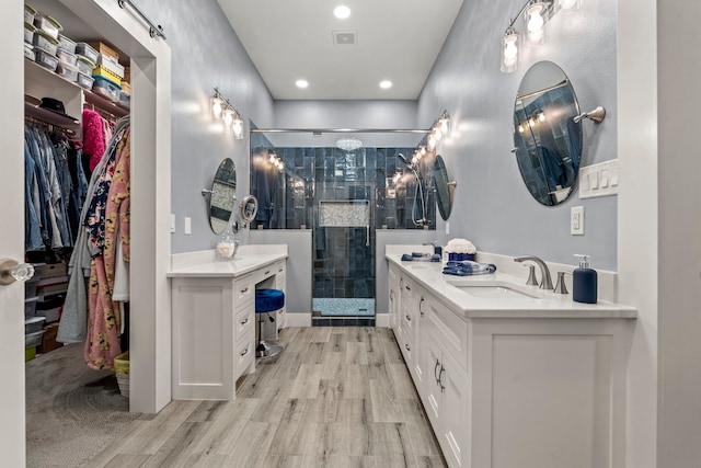 bathroom with double vanity, wood-type flooring, and a shower with shower door