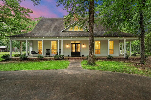 view of front of property with french doors, roof with shingles, and a porch