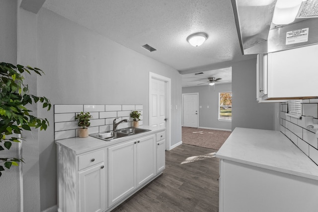 kitchen featuring decorative backsplash, sink, dark hardwood / wood-style flooring, white cabinetry, and a textured ceiling