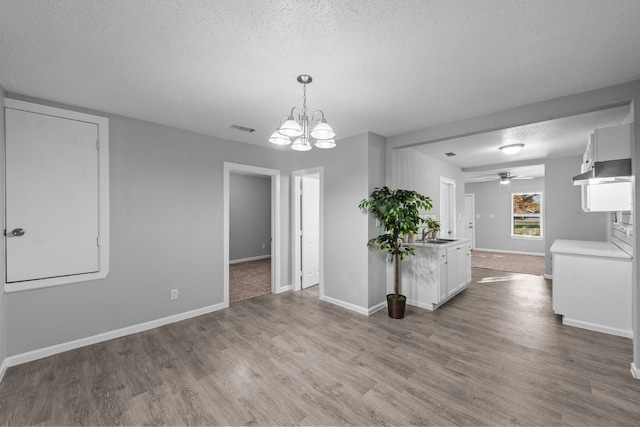 interior space featuring pendant lighting, sink, a textured ceiling, white cabinetry, and light hardwood / wood-style floors