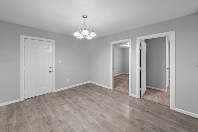 spare room featuring light hardwood / wood-style floors, a notable chandelier, and a textured ceiling