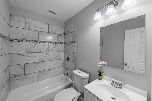 full bathroom featuring tiled shower / bath, vanity, a textured ceiling, and toilet