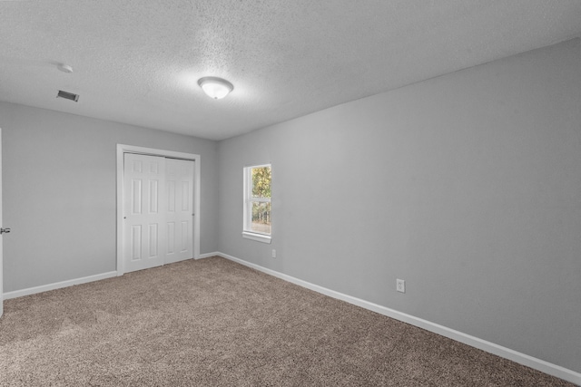 carpeted empty room with a textured ceiling