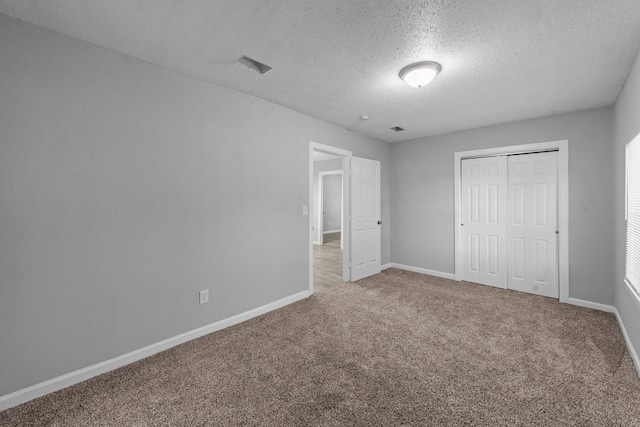 unfurnished bedroom featuring a textured ceiling, a closet, and carpet flooring