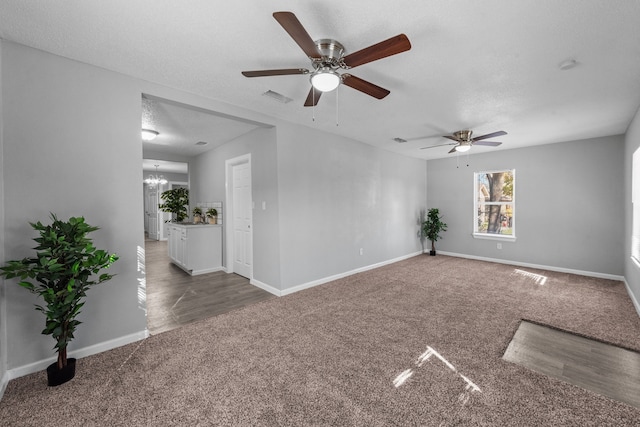 carpeted spare room with ceiling fan with notable chandelier and a textured ceiling