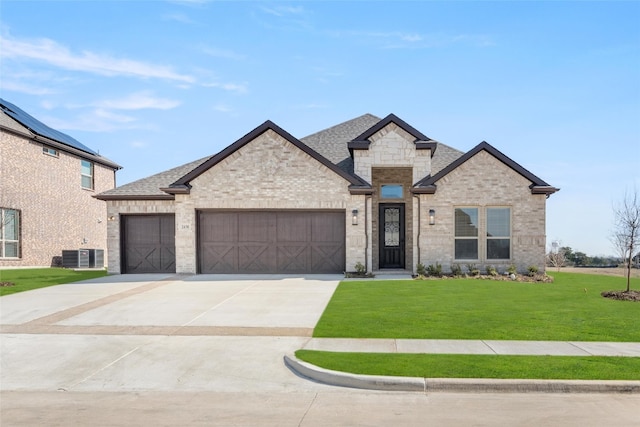 view of front of home with central air condition unit, a front lawn, and a garage