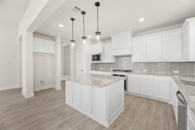 kitchen featuring white cabinetry, stainless steel appliances, tasteful backsplash, and light hardwood / wood-style flooring