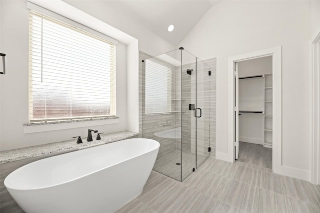 bathroom featuring independent shower and bath, tile floors, vaulted ceiling, and a wealth of natural light