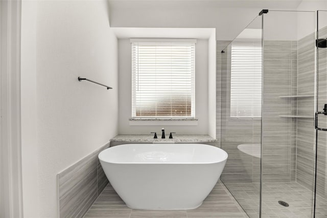 bathroom with tile walls, separate shower and tub, and tile floors