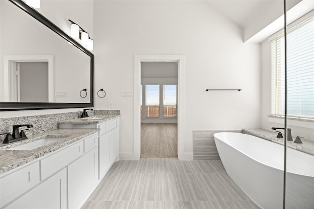 bathroom with tile flooring, a bathing tub, and dual bowl vanity