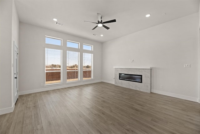 unfurnished living room featuring light wood-type flooring, ceiling fan, and a tiled fireplace