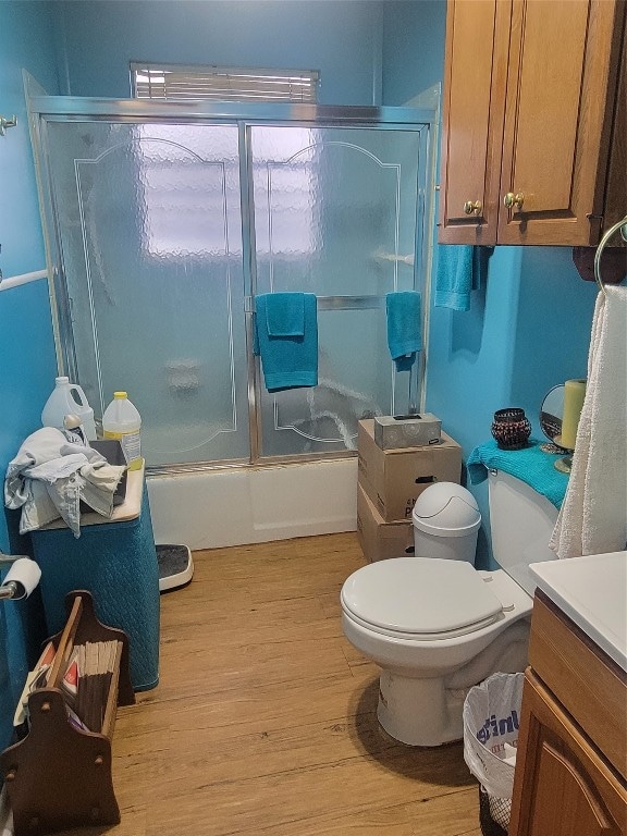 bathroom featuring hardwood / wood-style floors, toilet, and bath / shower combo with glass door