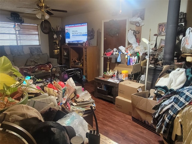 miscellaneous room featuring ceiling fan, a wood stove, and hardwood / wood-style flooring