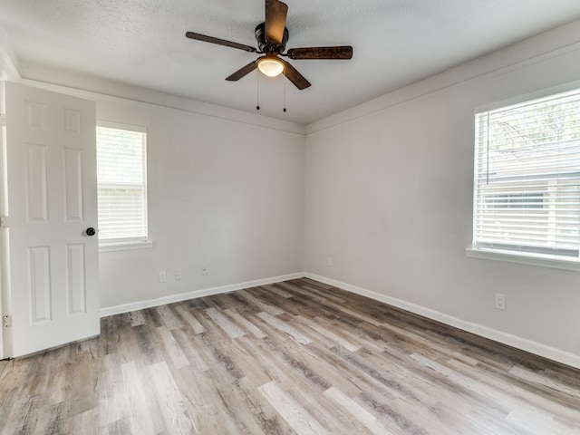 spare room featuring light hardwood / wood-style floors, ceiling fan, and a textured ceiling