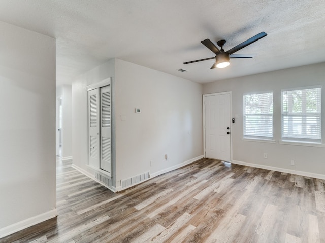 foyer entrance with light hardwood / wood-style floors, ceiling fan, and a textured ceiling