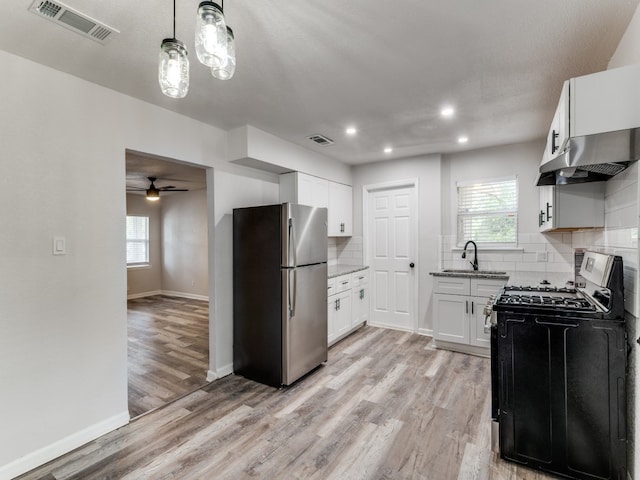 kitchen featuring black range with gas cooktop, stainless steel refrigerator, backsplash, and light hardwood / wood-style flooring