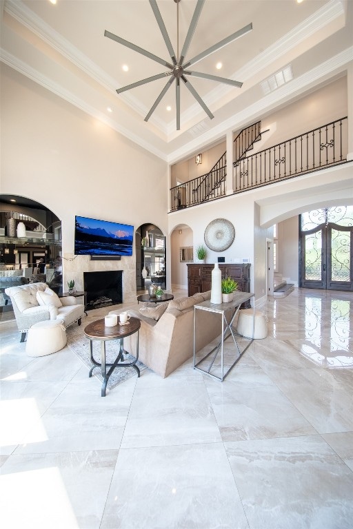 living room with french doors, a high end fireplace, crown molding, and a high ceiling