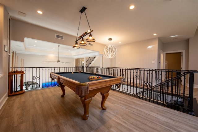 playroom featuring hardwood / wood-style flooring, ornamental molding, pool table, ceiling fan, and a tray ceiling