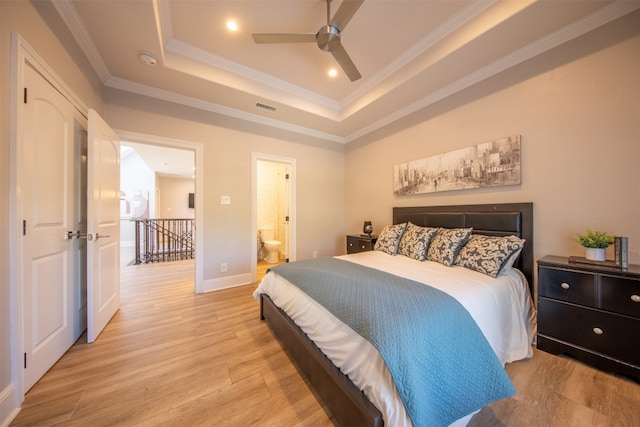 bedroom featuring crown molding, ceiling fan, ensuite bathroom, light hardwood / wood-style floors, and a raised ceiling