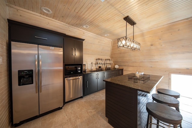 kitchen with stainless steel appliances, a center island, decorative light fixtures, wooden ceiling, and wood walls