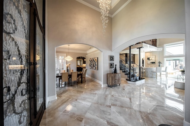 entryway featuring an inviting chandelier, a towering ceiling, and ornamental molding