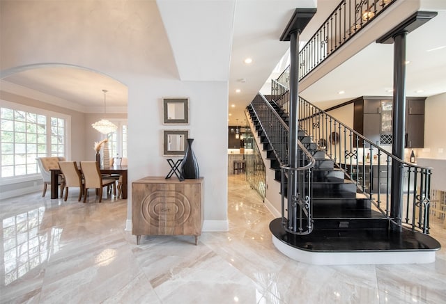 staircase with crown molding and a chandelier