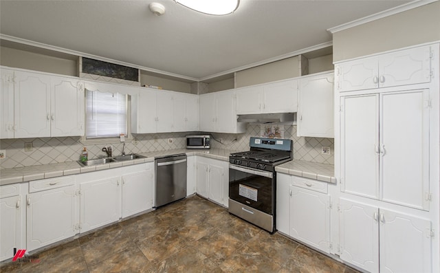 kitchen with white cabinetry, appliances with stainless steel finishes, tile countertops, dark tile flooring, and tasteful backsplash