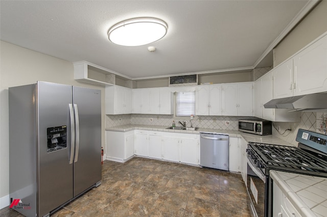 kitchen featuring dark tile flooring, white cabinets, appliances with stainless steel finishes, tile countertops, and tasteful backsplash