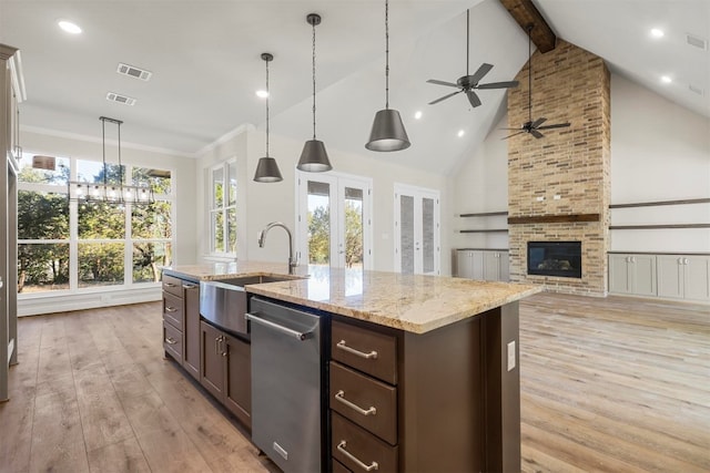 kitchen with light hardwood / wood-style flooring, a center island with sink, ceiling fan, and a stone fireplace