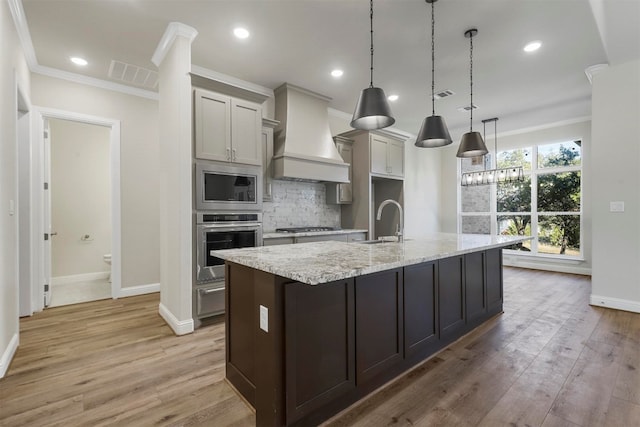 kitchen with stainless steel appliances, light wood-type flooring, tasteful backsplash, and custom exhaust hood